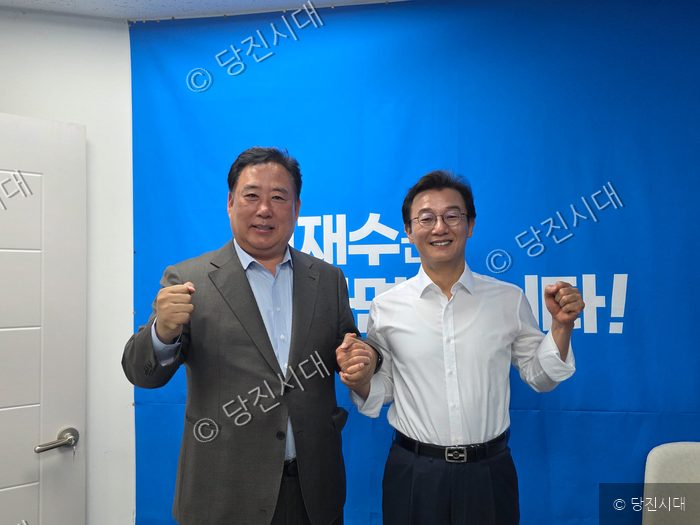 전재수 후보 등이 파란색 배경 앞에서 손을 맞잡고 주먹을 쥐어 보이며 포즈를 취하고 있다.