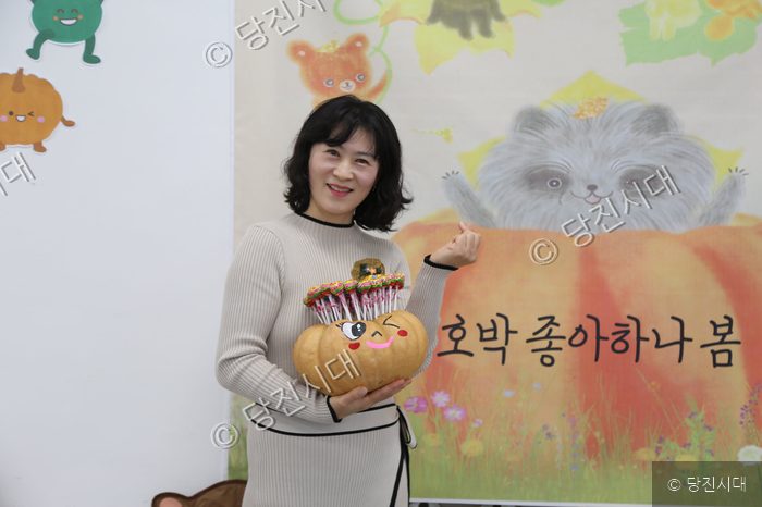 평화어린이집 원감이 호박 공예품을 들고 미소 짓고 있다.