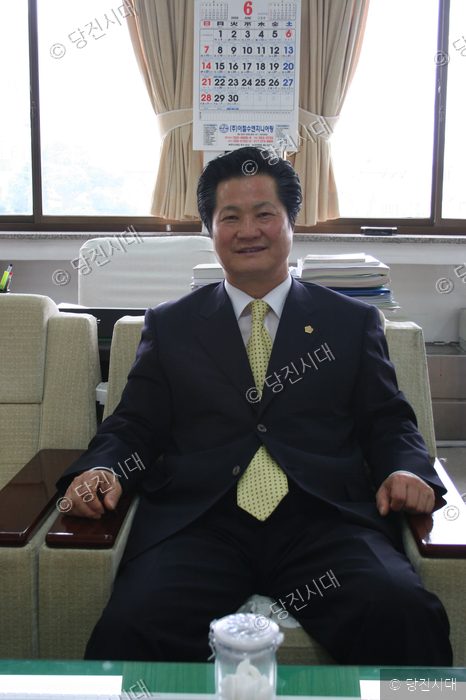 한창준 위원장이 의자에 앉아 미소 짓고 있다.