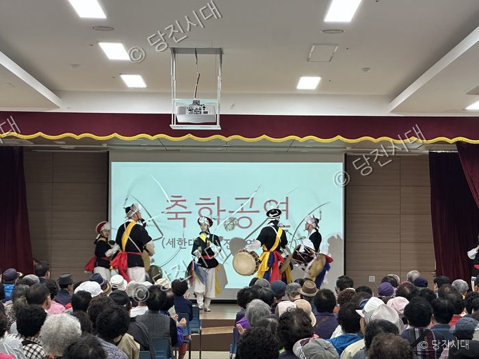 실내 강당에서 한복을 입은 공연단이 어르신들을 위한 축하공연을 펼치고 있다.
