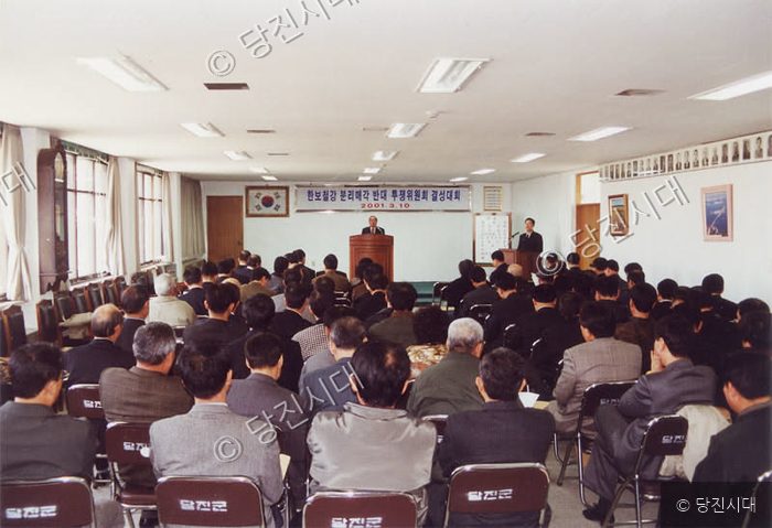 사람들이 강당에 모여 회의와 행사를 진행하고 있다.
