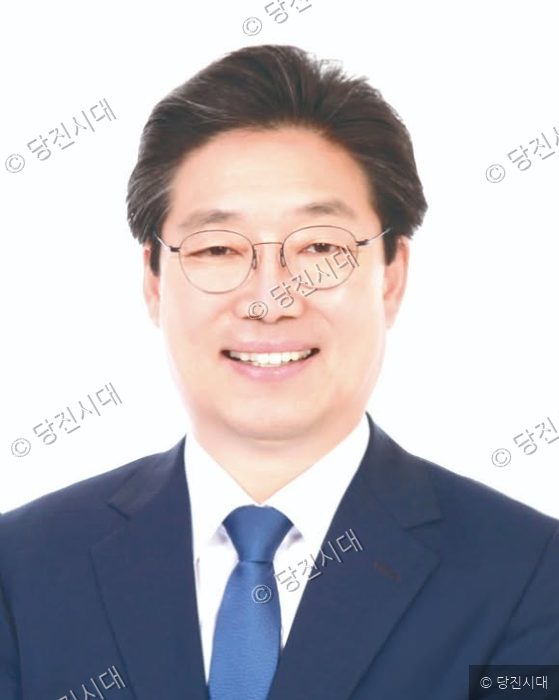 김홍장 전 당진시장이 정장 차림으로 미소 짓고 있다.