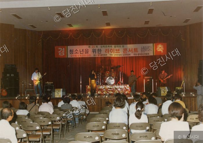 실내 무대에서 밴드가 청소년을 위한 라이브 콘서트를 하고 있다.