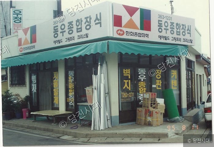 간판과 자재들이 늘어선 상점 전경을 보여주고 있다.