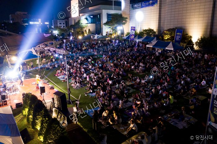많은 시민들이 야외 잔디밭에서 열린 치맥콘서트 공연을 즐기고 있다.