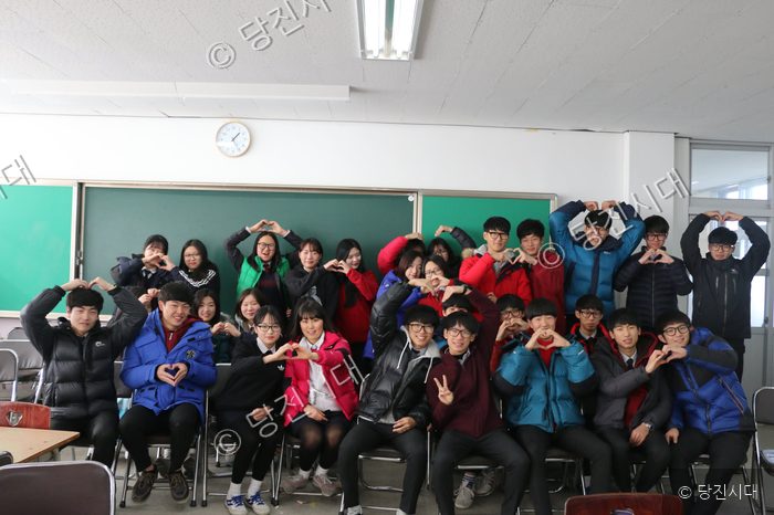 신평고등학교 학생들이 교실에서 하트 모양을 만들며 포즈를 취하고 있다.
