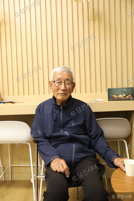 신양웅 전 석문중학교 교장이 의자에 앉아 미소 짓고 있다.