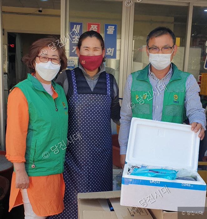 송산면에서 봉사자들이 물품을 전달하며 포즈를 취하고 있다.