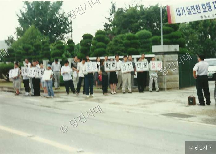 주민들이 학교 앞에서 피켓을 들고 시위를 하고 있다.