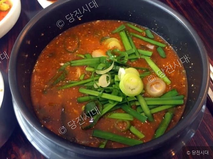 뚝배기에 담긴 얼큰한 어죽 위에 파와 부추가 얹혀 있다.