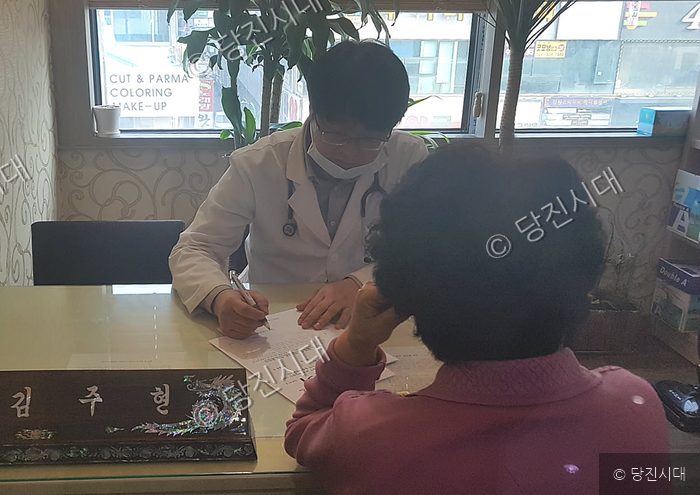 의사가 진료실에서 환자와 상담하며 서류를 작성하고 있다.