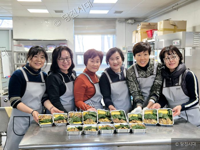 육전 봉사단원들이 주방에서 직접 만든 도시락을 앞에 두고 함께 기념 촬영을 하고 있다.