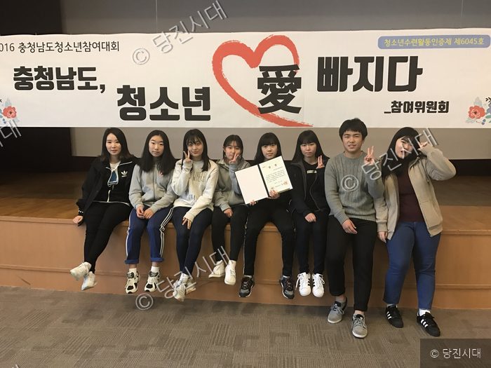 청소년들이 현수막 아래에서 상장을 들고 기념 촬영을 하고 있다.