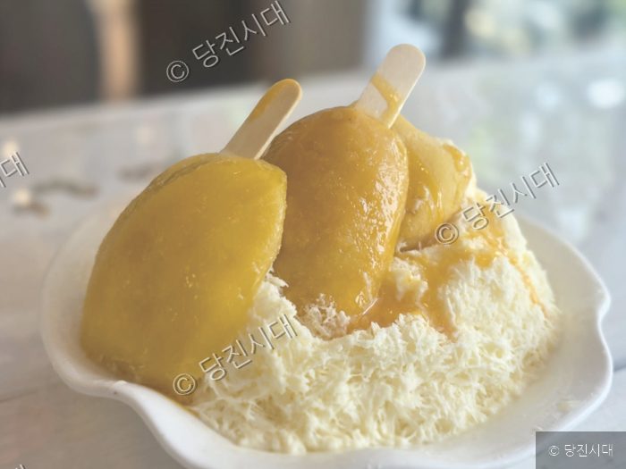 망고 아이스크림이 얹어진 빙수가 그릇에 담겨 있다.