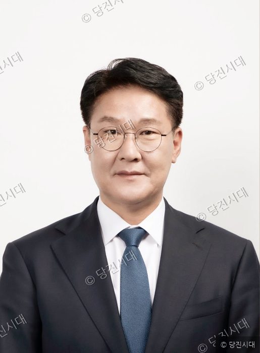 정장 차림의 지역구 도의원이 정면을 바라보며 미소 짓고 있다.