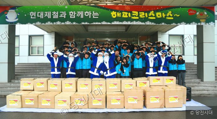 현대제철 임직원들이 파란 산타 복장으로 봉사 물품과 함께 기념 촬영을 하고 있다.