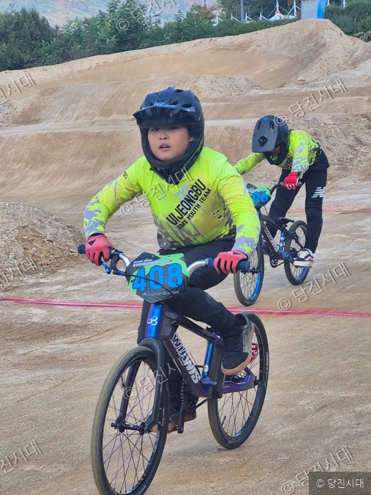 어린 선수가 BMX 자전거를 타고 트랙을 달리고 있다.