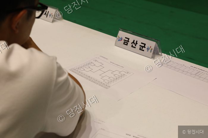 충남도민체전 종목별 대진표를 확인하는 참가자가 자리에 앉아 있다.