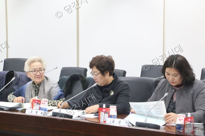 참석자들이 회의 테이블에 앉아 문서를 보고 있다.