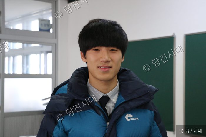 신평고등학교 학생들이 교내에서 밝은 표정으로 카메라를 바라보고 있다.