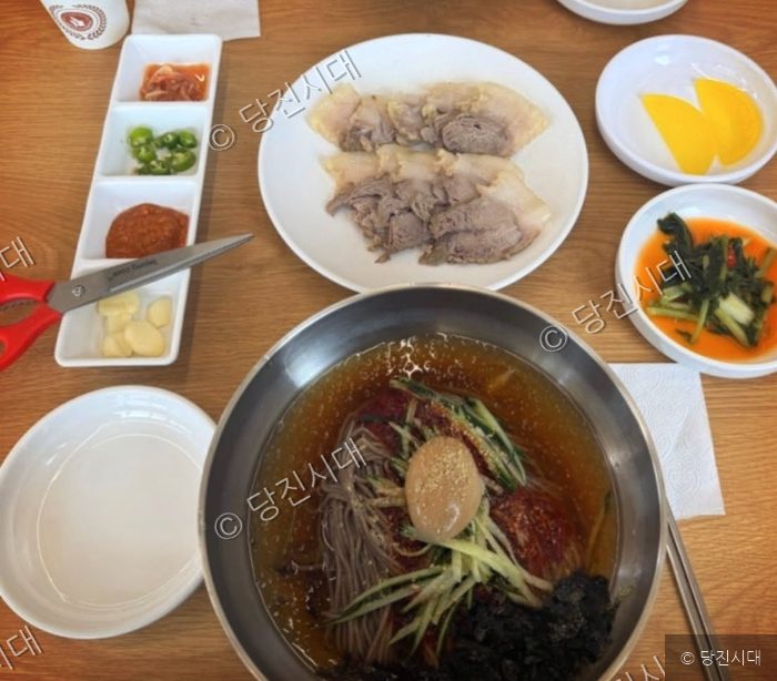 식당 테이블 위에 메밀국수와 수육이 놓여 있다.