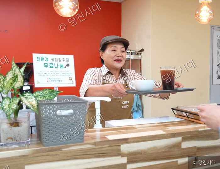 당진시니어클럽의 할할카페에서 한 어르신이 음료를 손님에게 건네고 있다.
