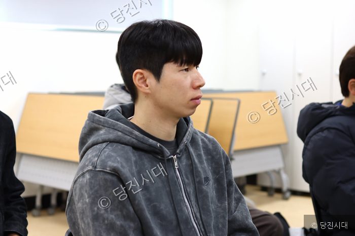 한상민 감독이 실내에서 진지한 표정으로 어딘가를 바라보고 있다.