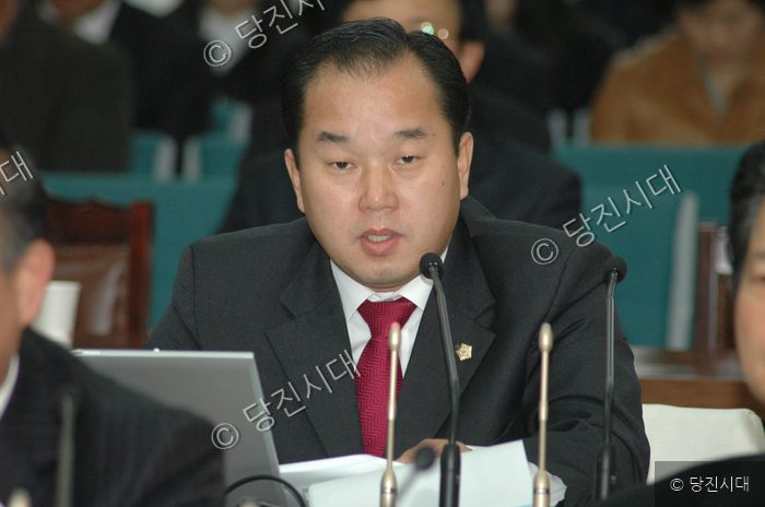 정장 차림의 최기환 씨가 회의 중에 발언하고 있다.