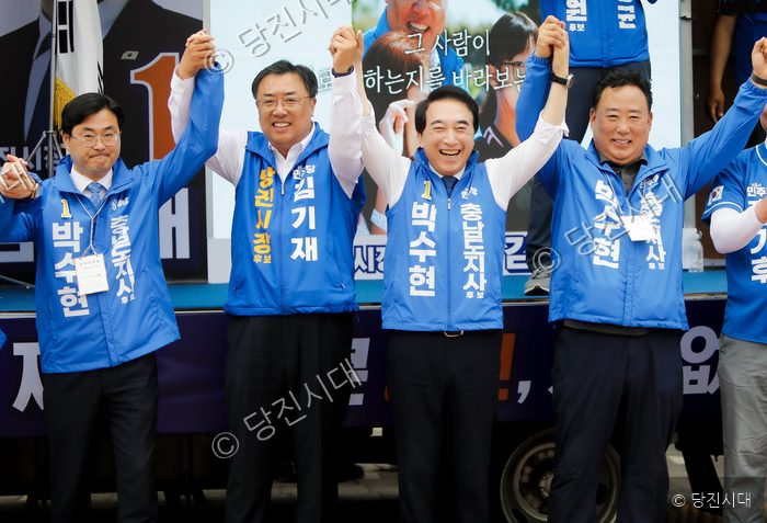 정치인들이 무대 위에서 손을 맞잡고 인사를 하고 있다.