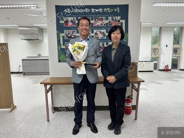 한 남성이 복지관 관계자로부터 감사패와 꽃다발을 받고 있다.