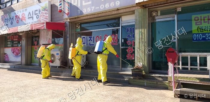 방역복을 입은 대원들이 상가 건물 앞에서 방역 소독 작업을 하고 있다.