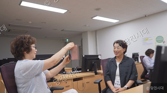 어르신들이 컴퓨터 교육 현장에서 스마트폰을 보며 소통하고 있다.