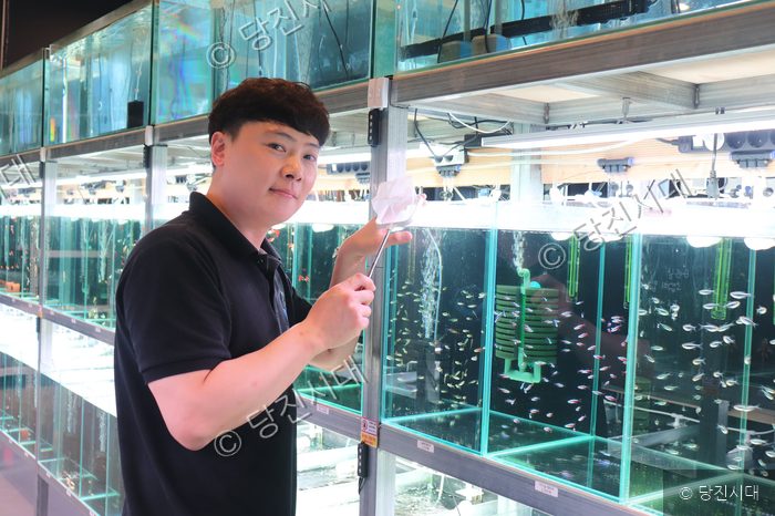 수족관 카페 대표가 수조 앞에서 뜰채를 들고 포즈를 취하고 있다.
