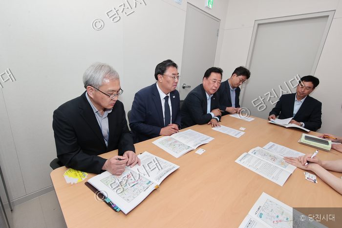 김기재 당진시장이 관계자들과 함께 회의실에 앉아 문서를 검토하고 있다.
