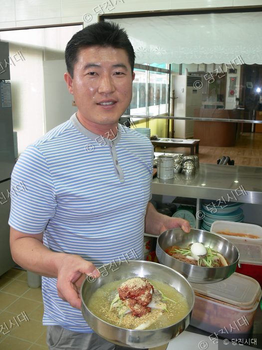 식당 대표가 직접 만든 함흥냉면 두 그릇을 들어 보이고 있다.