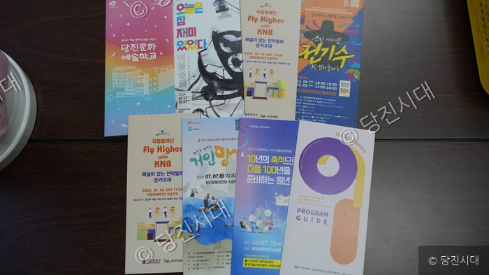 테이블 위에 당진문화재단 행사와 전시 안내 홍보물들이 놓여 있다.