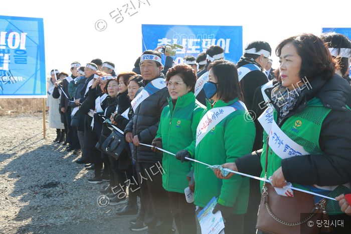 사람들이 길가에 일렬로 서서 행사를 진행하고 있다.