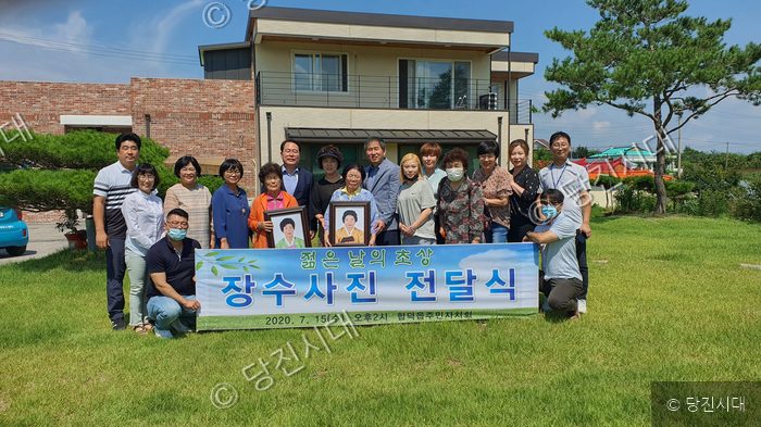 주민들이 합덕읍주민자치회의 장수사진 전달식에서 기념촬영을 하고 있다.