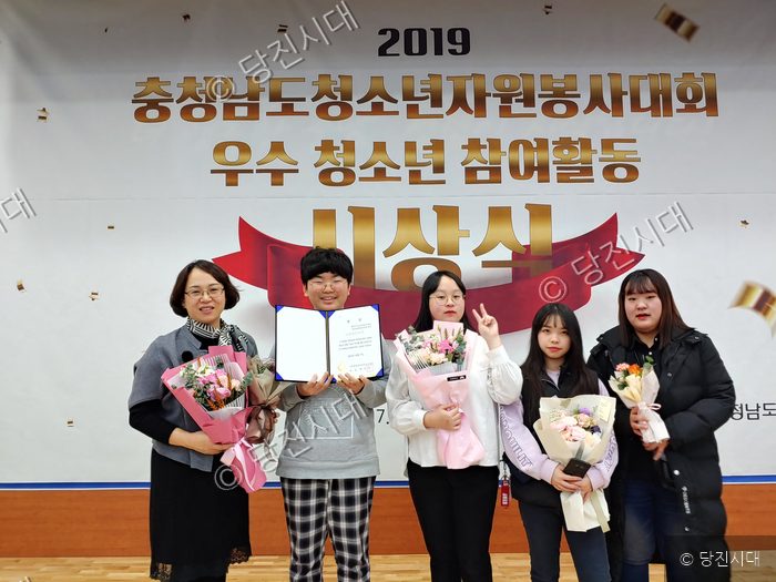 청소년들이 자원봉사대회에서 상장과 꽃다발을 들고 포즈를 취하고 있다.
