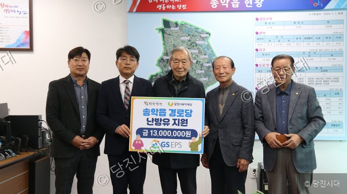 다섯 명의 남성이 송악읍 경로당 난방유 지원 기념 피켓을 들고 기념 촬영을 하고 있다.