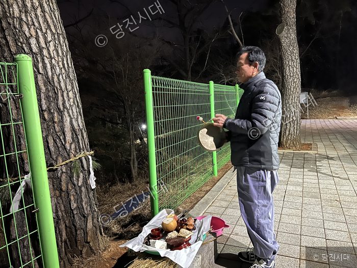 한 남성이 밤에 야외에서 제사를 지내고 있다.