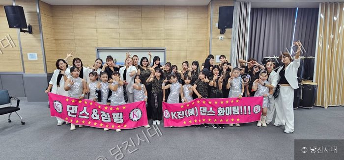 K진댄스&점핑학원 원장과 수강생들이 현수막을 들고 기념 촬영을 하고 있다.