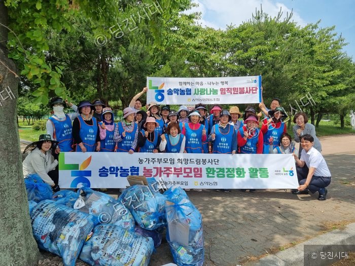 송악농협 임직원과 주부모임 회원들이 공원에서 환경정화 활동을 기념하고 있다.