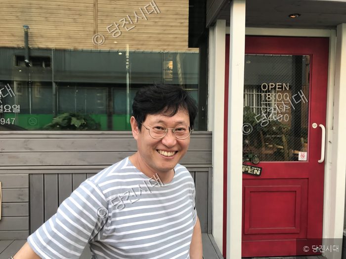 한 남성이 당진의 음식점 앞에서 밝게 미소 짓고 있다.