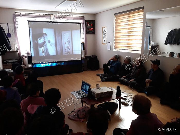 경로당에 모인 어르신들이 대형 스크린으로 영화를 관람하고 있다.