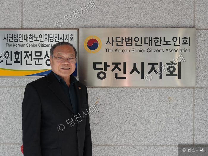 이영문 대한노인회 당진시지회장이 현판 앞에서 포즈를 취하고 있다.