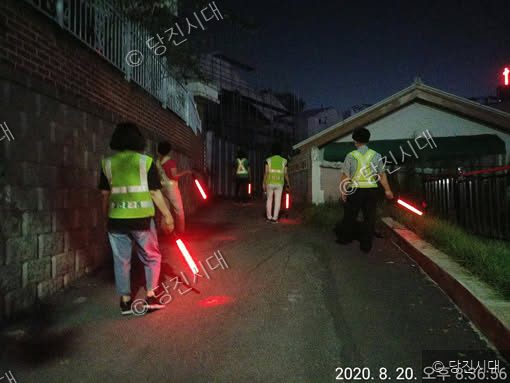 야간에 방범 조끼를 입은 자율방범대원들이 어두운 골목길을 순찰하고 있다.