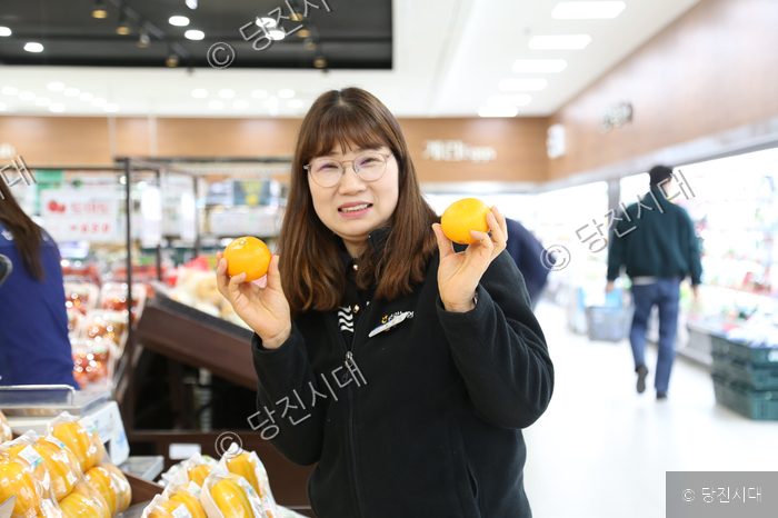황봉숙 송악농협 하나로마트 주임이 마트에서 오렌지를 들고 미소 짓고 있다.