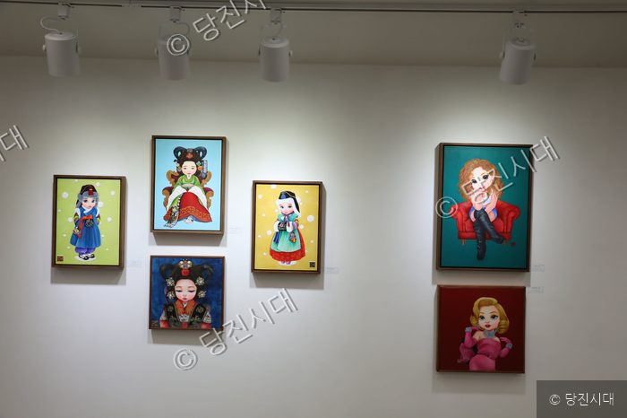 미술관 벽면에 다양한 인물과 베이비돌을 주제로 한 회화 작품들이 전시되어 있다.