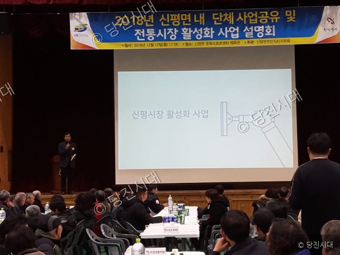 실내 강당에서 신평면 단체 사업 공유 및 전통시장 활성화 사업 설명회가 개최되고 있다.